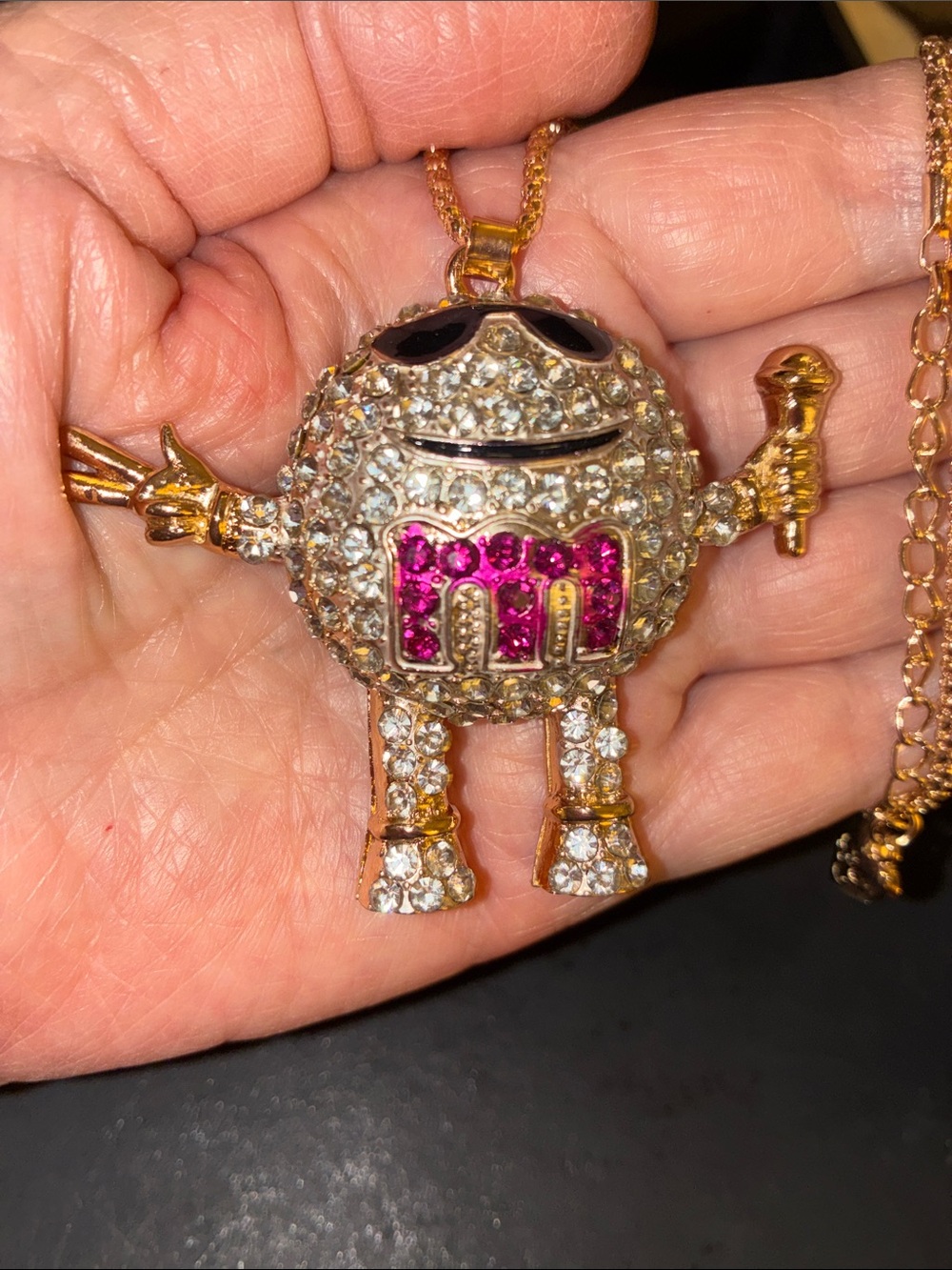 Pink & Clear Crystal M&M Holding A Microphone And Throwing Out A Peace sign